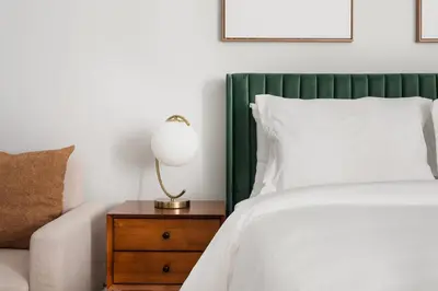 a bed with a green headboard and a table with a lamp at 73-310 Newly Reno Studio UWS Doorman Gym Laundry in New York