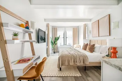 a bedroom with a bed and a table and chairs at 73-304 Newly Reno Studio UWS Doorman Gym Laundry in New York