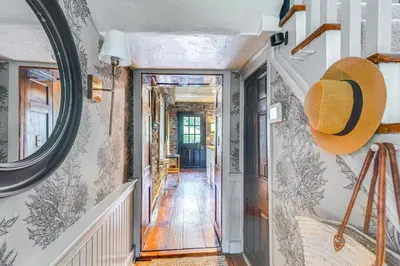 a hallway with a mirror on the wall and a staircase at Steps to Delaware Canal Enchanting Stone Cottage! in Kintnersville