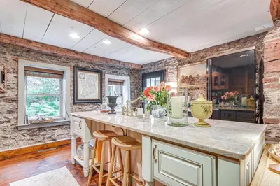 a kitchen with a large counter with stools at Steps to Delaware Canal Enchanting Stone Cottage! in Kintnersville