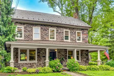 a brick house with an american flag in the yard at Steps to Delaware Canal Enchanting Stone Cottage! in Kintnersville