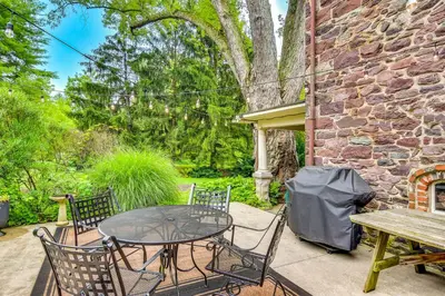 a patio with a table and chairs and a brick building at Steps to Delaware Canal Enchanting Stone Cottage! in Kintnersville