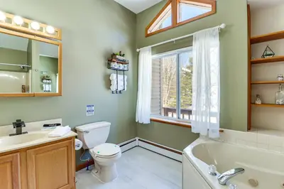 a bathroom with a tub and a toilet and a window at Private Hot Tub Lakefront Poconos Home! in Pocono Summit
