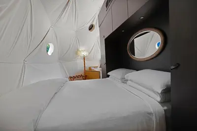a bedroom with a large white bed with a round mirror at Domes at Catskills in Swan Lake