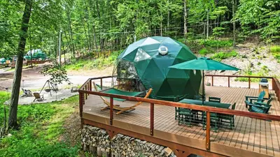 a tent with chairs and an umbrella on a deck at Domes at Catskills in Swan Lake