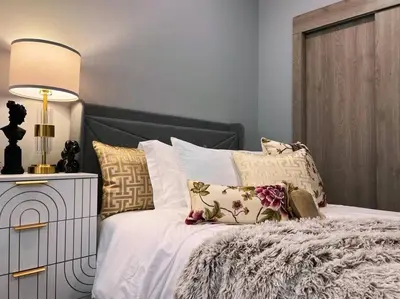 a bedroom with a bed with pillows and a lamp at Spacious & Stylish 2BR 2BA - Easy NYC Commute in Jersey City