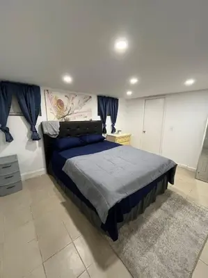 a bedroom with a bed with a blue comforter at 2 Bedroom Apartment By AirportS in Hillside