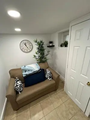 a couch in a room with a clock on the wall at 2 Bedroom Apartment By AirportS in Hillside