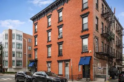 two cars parked in front of a brick building at Hoboken 15 Min Train to Manhattan Full Kitchen in Hoboken