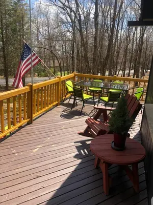 a deck with chairs and an american flag and a table at That Gray House Romantic getaway in Albrightsville