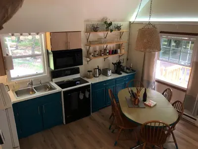 a kitchen with blue cabinets and a table with a dining room at That Gray House Romantic getaway in Albrightsville