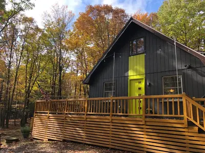 a black house with a green door on a deck at That Gray House Romantic getaway in Albrightsville
