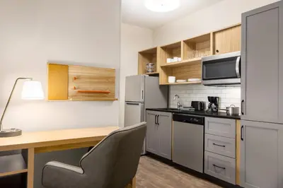 a small kitchen with a desk and a refrigerator at Candlewood Suites Lawrenceville - Princeton by IHG in Lawrenceville