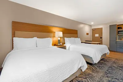 two beds in a hotel room with white sheets at Candlewood Suites Lawrenceville - Princeton by IHG in Lawrenceville