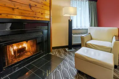 a living room with a fireplace and a chair at BEST WESTERN PLUS Poconos in Tannersville