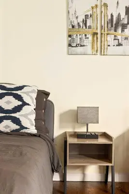a bedroom with a bed and a nightstand with a lamp at Newark Gem Pearl 3BR, 2BA - Sleeps 10 - Walk to Prudential Center and Newark Penn Station, Near EWR and American Dream Mall, includes WiFi - Laundry - Backyard - Gym in Newark