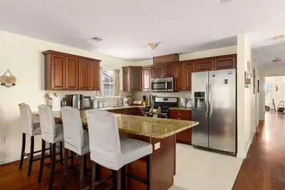 a kitchen with a island with bar stools and a refrigerator at Newark Gem Pearl 3BR, 2BA - Sleeps 10 - Walk to Prudential Center and Newark Penn Station, Near EWR and American Dream Mall, includes WiFi - Laundry - Backyard - Gym in Newark