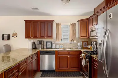 a kitchen with wooden cabinets and stainless steel appliances at Newark Gem Pearl 3BR, 2BA - Sleeps 10 - Walk to Prudential Center and Newark Penn Station, Near EWR and American Dream Mall, includes WiFi - Laundry - Backyard - Gym in Newark