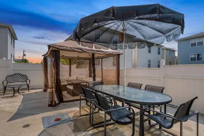 a patio with a table and a large umbrella at Newark Gem Pearl 3BR, 2BA - Sleeps 10 - Walk to Prudential Center and Newark Penn Station, Near EWR and American Dream Mall, includes WiFi - Laundry - Backyard - Gym in Newark