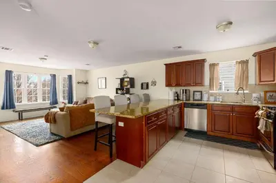 a kitchen with wooden cabinets and a living room at Newark Gem Pearl 3BR, 2BA - Sleeps 10 - Walk to Prudential Center and Newark Penn Station, Near EWR and American Dream Mall, includes WiFi - Laundry - Backyard - Gym in Newark