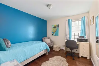 a blue bedroom with a bed and a desk at Newark Gem Ruby 3BR, 3BA - Sleeps 14 - Walk to Prudential Center and Newark Penn Station, Near EWR and American Dream Mall, includes Parking - WiFi - Laundry - Backyard - Gym in Newark