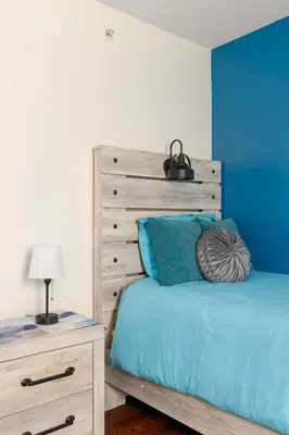 a bedroom with a bed with a blue wall at Newark Gem Ruby 3BR, 3BA - Sleeps 14 - Walk to Prudential Center and Newark Penn Station, Near EWR and American Dream Mall, includes Parking - WiFi - Laundry - Backyard - Gym in Newark