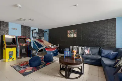 a living room with a couch and a video game at Newark Gem Ruby 3BR, 3BA - Sleeps 14 - Walk to Prudential Center and Newark Penn Station, Near EWR and American Dream Mall, includes Parking - WiFi - Laundry - Backyard - Gym in Newark