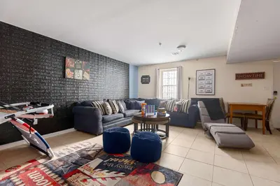 a living room with blue couches and a brick wall at Newark Gem Ruby 3BR, 3BA - Sleeps 14 - Walk to Prudential Center and Newark Penn Station, Near EWR and American Dream Mall, includes Parking - WiFi - Laundry - Backyard - Gym in Newark
