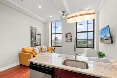 a kitchen with a sink and a living room at Luxury 1BR - Glass Wall & Window in Philadelphia