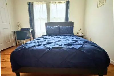 a bed with a blue comforter in a bedroom at Belmont Suites - BR 2 (Private Room) - 30 mins to NYC in Newark