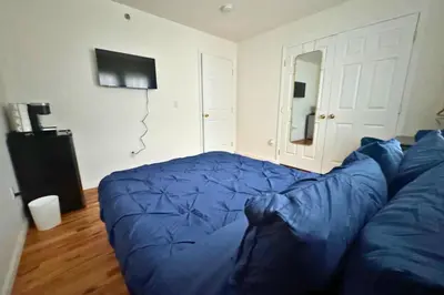 a living room with a blue couch and a television at Belmont Suites - BR 2 (Private Room) - 30 mins to NYC in Newark