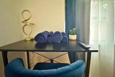 a table with a blue chair and a table with a remote at Belmont Suites - BR 2 (Private Room) - 30 mins to NYC in Newark