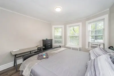 a bedroom with a bed and a desk and windows at Happiness in Harrison in Harrison