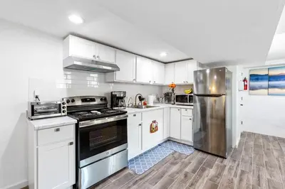 a kitchen with white cabinets and a stainless steel refrigerator at Luxury Suite by Prudential Ctr & 7min to EWR Airpt in Newark