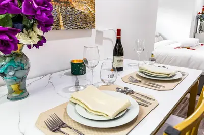 a table with plates and glasses and a vase with purple flowers at Luxury Suite by Prudential Ctr & 7min to EWR Airpt in Newark