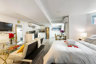 a bedroom with a large bed and a kitchen at Luxury Suite by Prudential Ctr & 7min to EWR Airpt in Newark