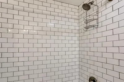 a bathroom with white tiled walls and a shower at Walk to Mohican Lake Catskills Getaway with Dock! in Glen Spey
