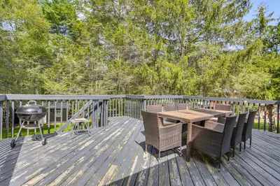 a wooden deck with a table and chairs and a grill at Walk to Mohican Lake Catskills Getaway with Dock! in Glen Spey