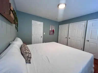 a bedroom with a white bed with two white doors at Urban Zen in Montclair