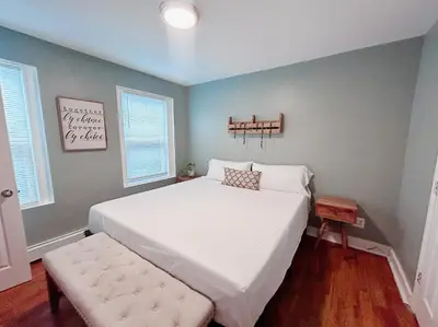 a bedroom with a large white bed and a bench at Urban Zen in Montclair