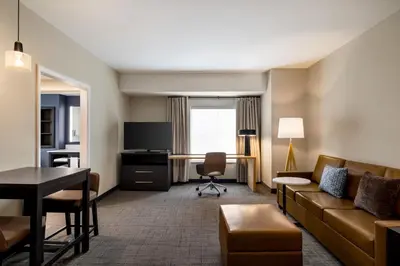 a hotel room with a couch and a desk and a table at Residence Inn by Marriott Mechanicsburg in Mechanicsburg