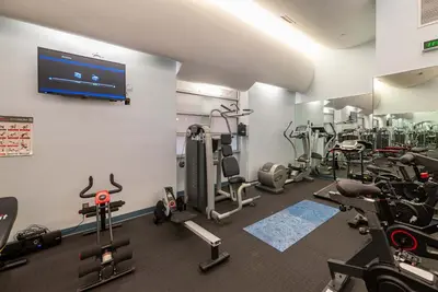 a gym with several tread machines and a flat screen tv at Stunning Condo in Heart of New York with GYM & MORE in New York