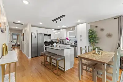 a kitchen with white cabinets and a table with chairs at Luxury Gated home near NYC and EWR with free Parking in Elizabeth