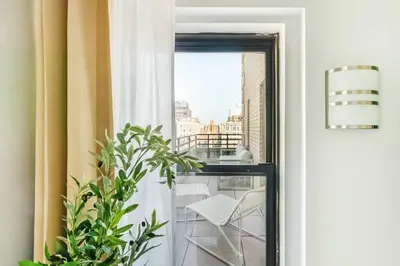 a room with a window and a white chair on a balcony at 73-1504 Newly Reno Studio UWS Doorman Gym Laundry in New York