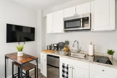 a white kitchen with a sink and a microwave at 73-1504 Newly Reno Studio UWS Doorman Gym Laundry in New York