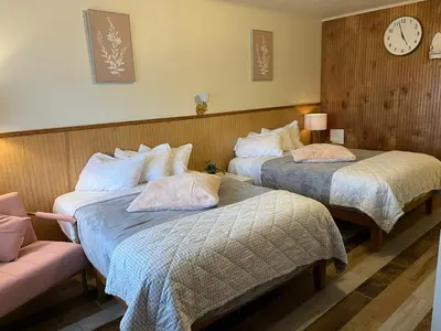two beds in a hotel room with a clock on the wall at High Point Mountain Motel in Wantage