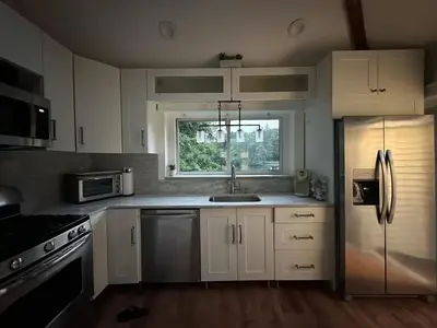 a kitchen with white cabinets and a stainless steel refrigerator at Lovely private home in a serene neighborhood in Totowa