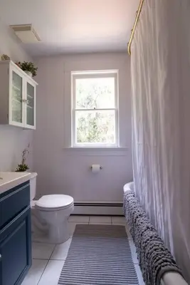 a white bathroom with a toilet and a window at Dancing Doe Estate - Delaware Valley Escape with Wood Stove and Hot Tub in Jeffersonville