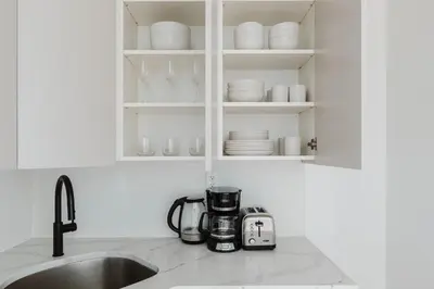 a kitchen counter with a coffee maker and plates on shelves at Blueground Greenpoint wd ac near ferry NYC-1538 in New York