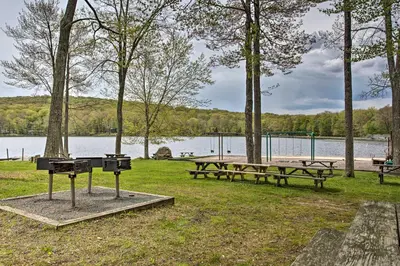 a park with picnic tables and a grill next to a lake at Pocono Lake Retreat Ski and Explore at Pine Loch! in Pocono Lake